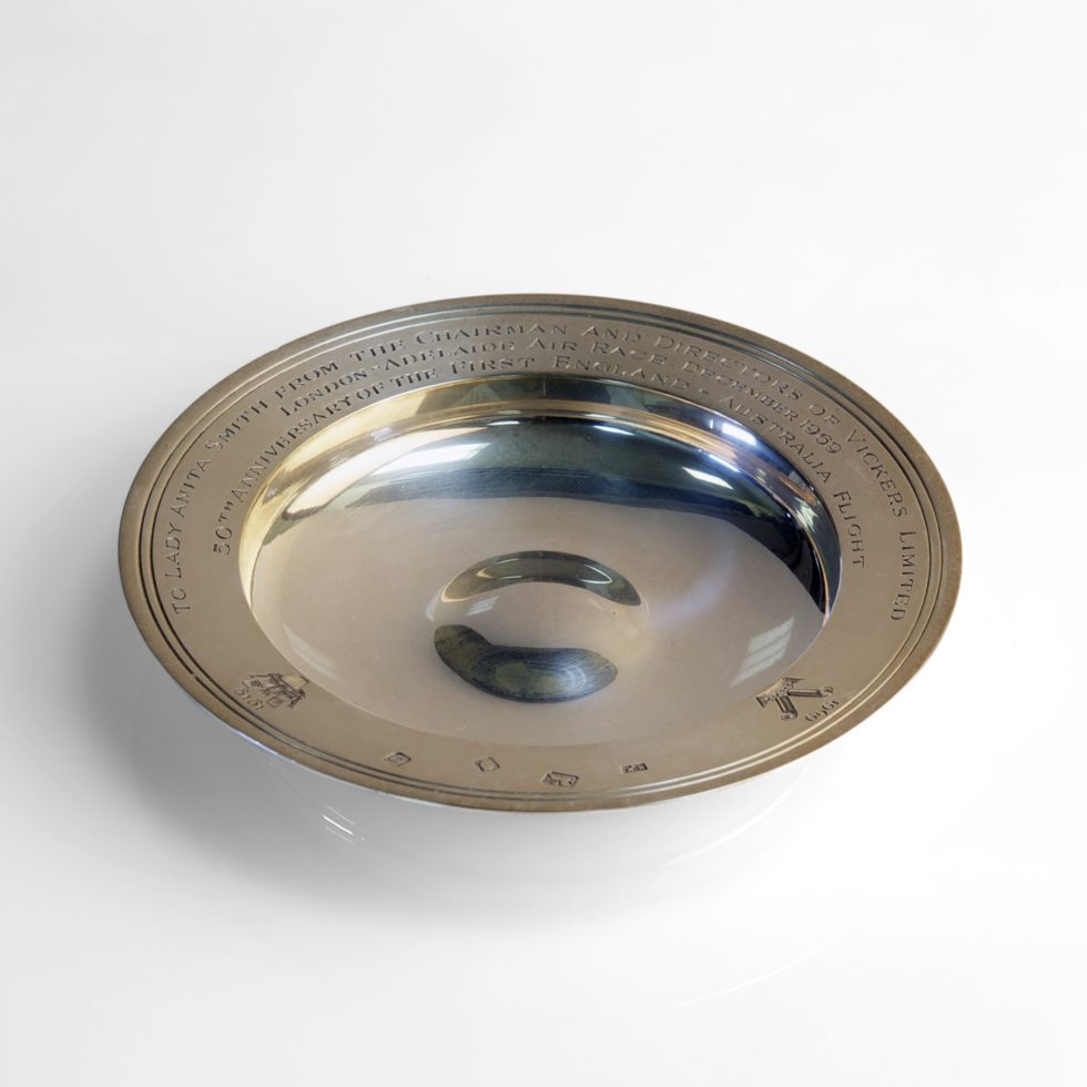 Image: silver dish featuring engraving around its lip. The engraving includes maker's marks and the logo of Vickers for both 1919 and 1969.