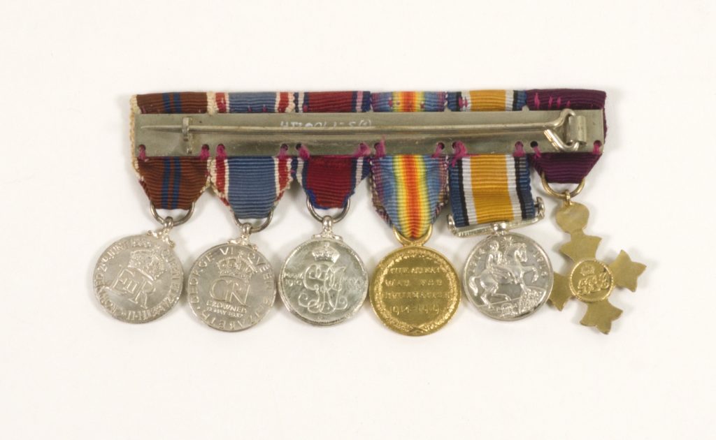 Image: six medals and ribbons aligned and seen from reverse side.