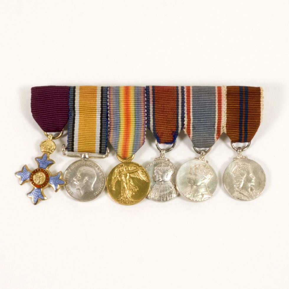 Image: 6 medals and ribbons aligned. Five of the six are circular and the sixth is a cross with a circular middle and a crown on top.