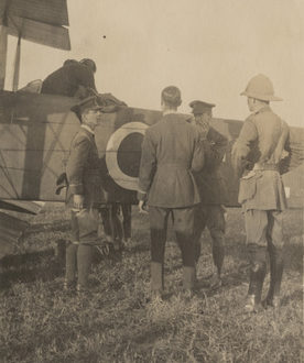 Image: men standing around the tail of a biplane.