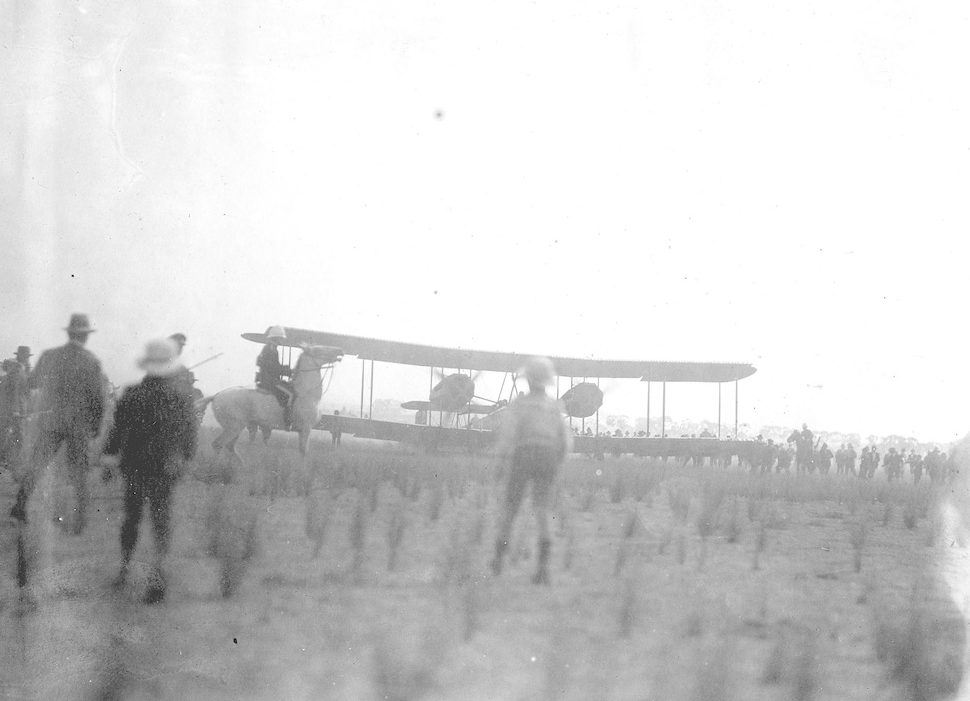 Image: biplane landing with people watching