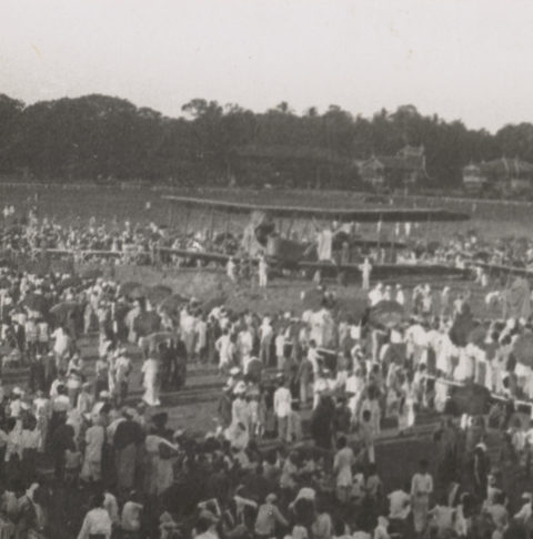 Image: Biplane on open field surrounded by onlookers