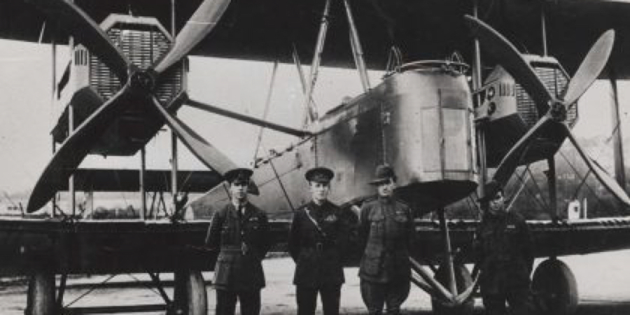 Four flight crew members standing in front of the large bi-plane